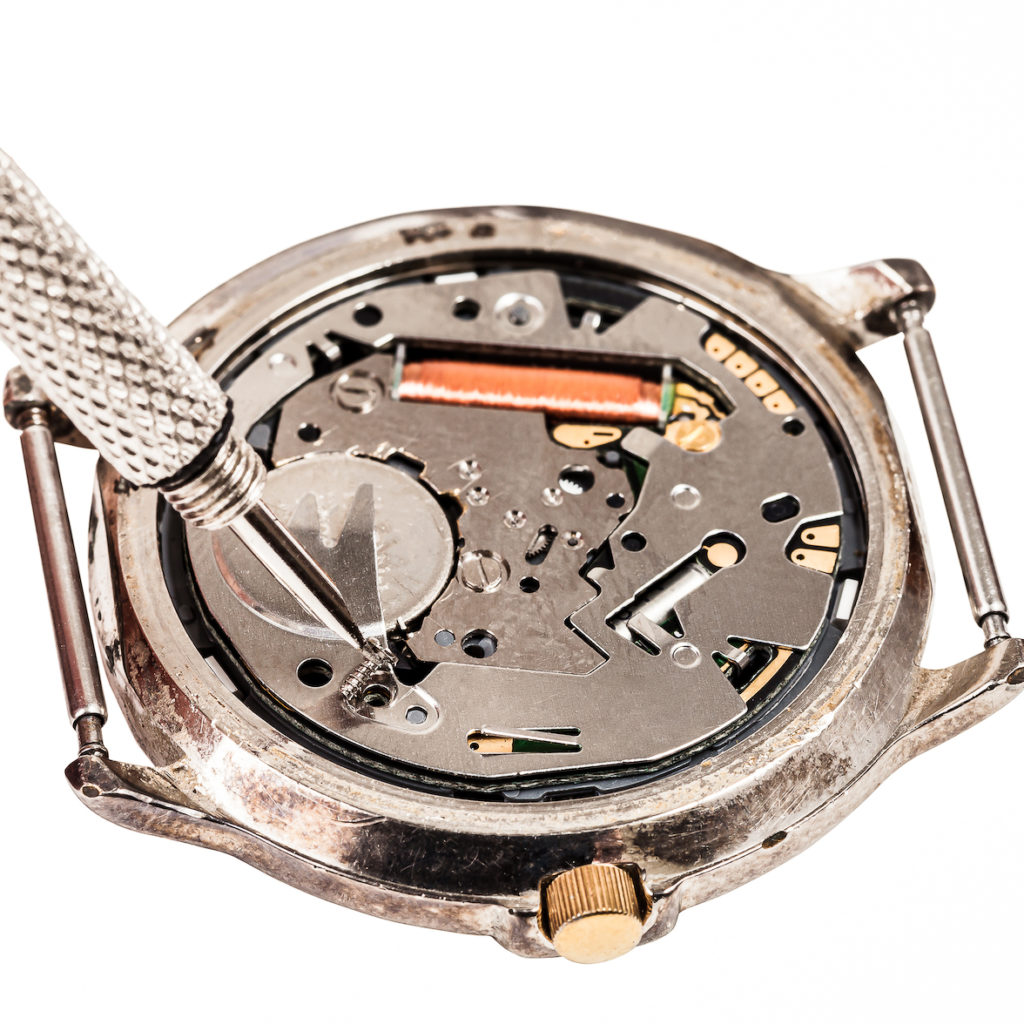 Image showcasing back of watch with battery and tool