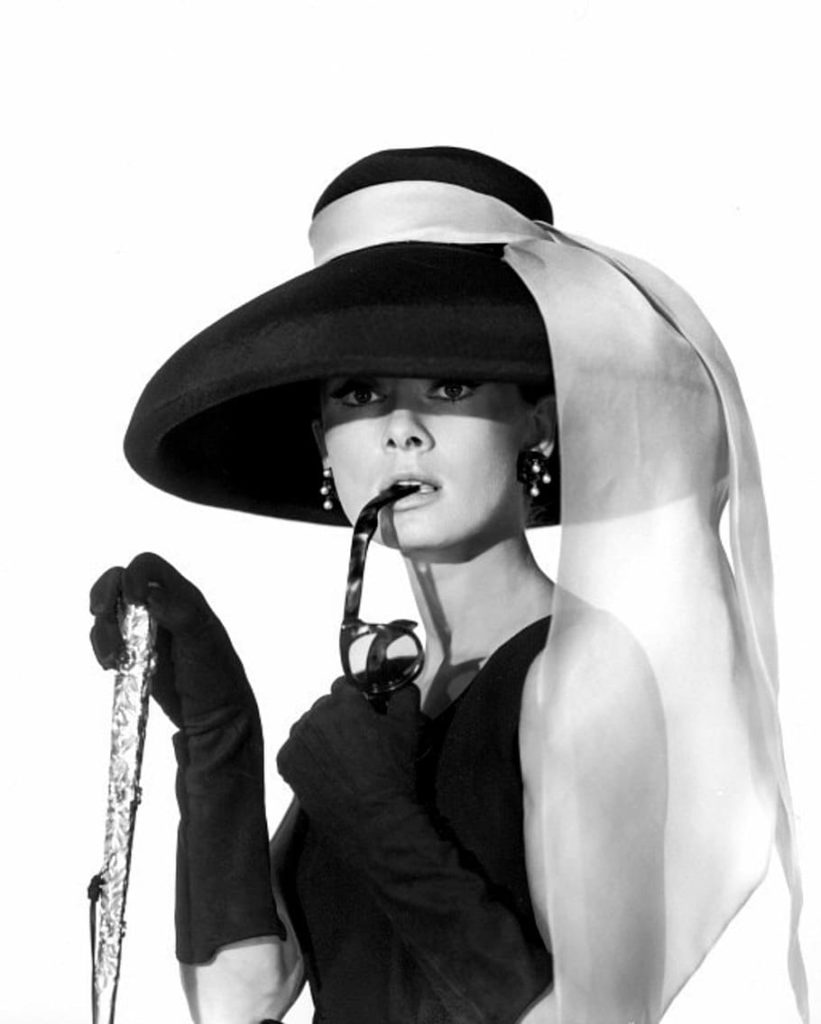 Black and white image showcasing 1960s actress Audrey Hepburn from photoshoot for "Breakfast at Tiffany's" wearing oversized plastic earrings.