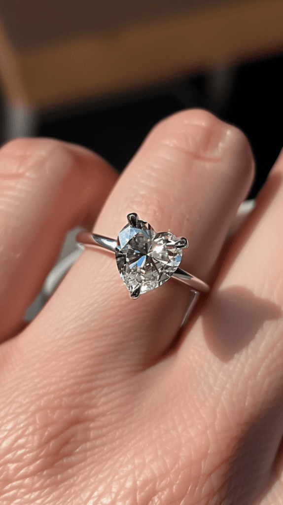 Photo showcasing heart-shaped diamond engagement ring on ring finger