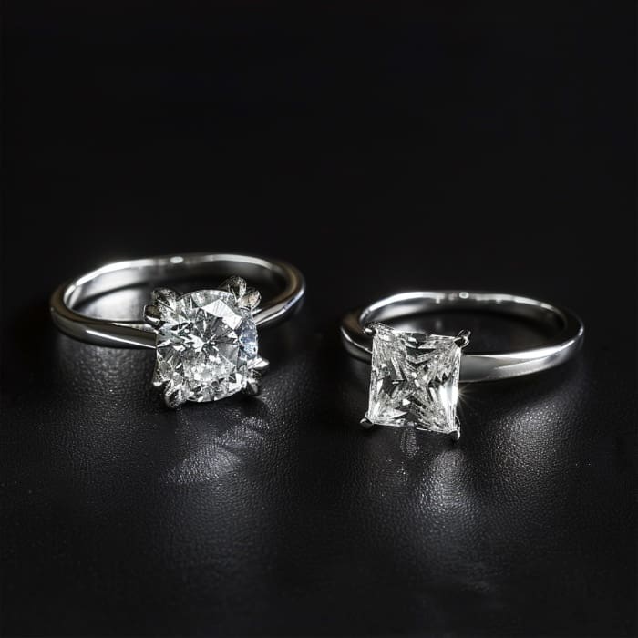 Photo of round brilliant cut diamond engagement ring and princess cut diamond engagement ring on plain black background