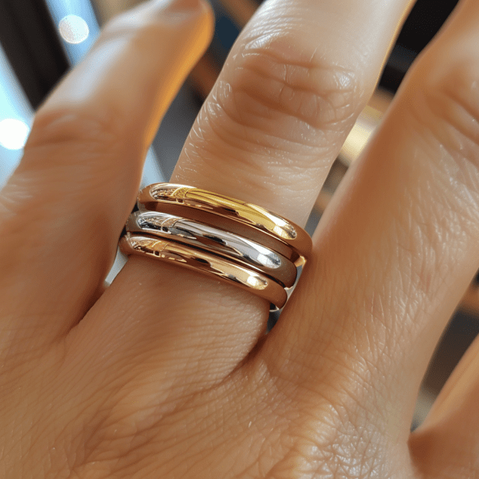 Photo of white gold, yellow gold, and rose gold rings stacked on ring finger.