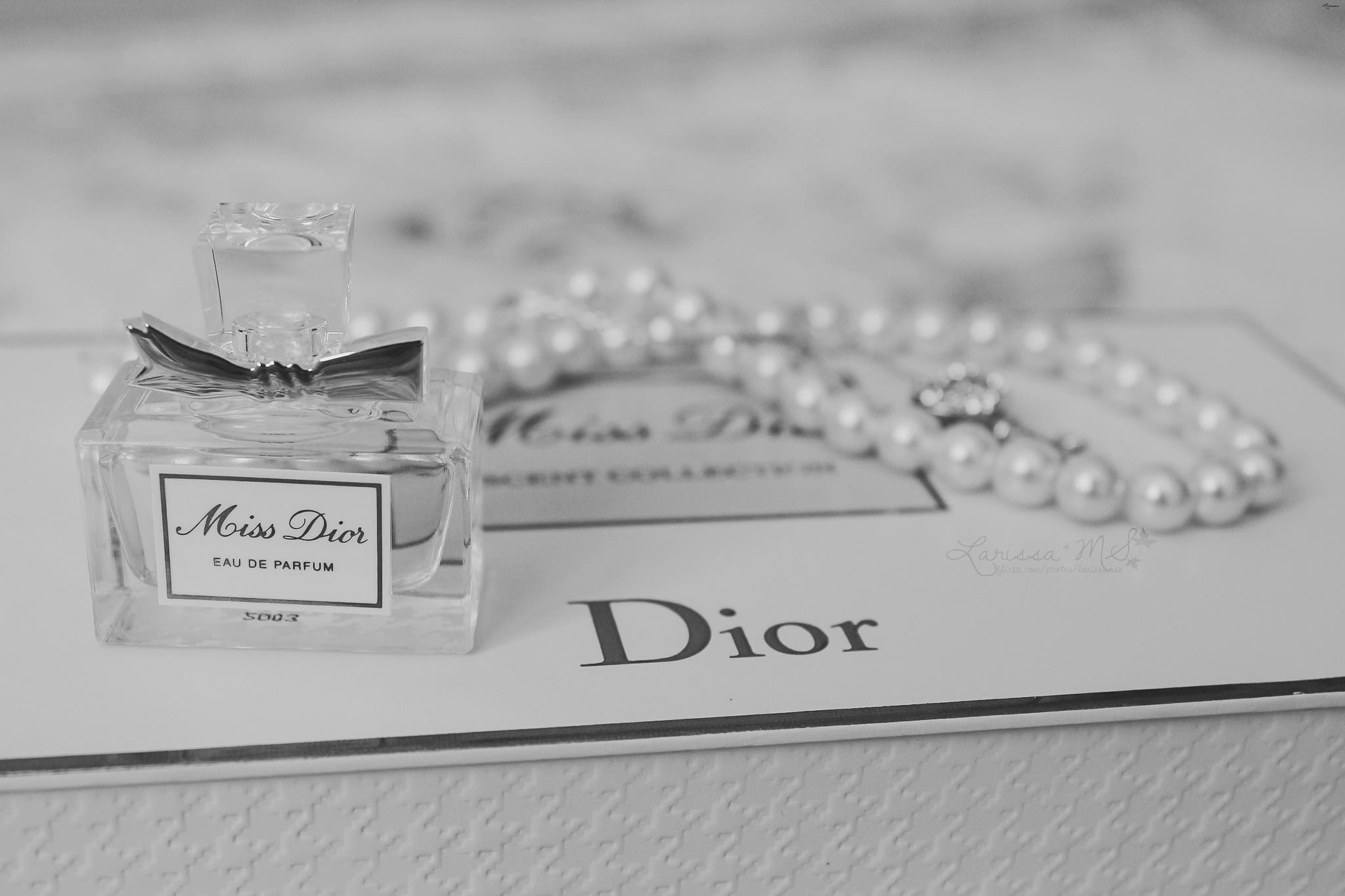 Image showcasing Miss Dior perfume and pearl necklace on Dior box with logo