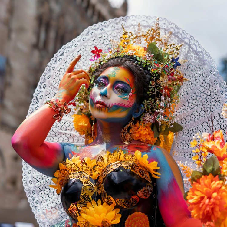 Image of woman wearing day of the dead colorful skull makeup, flower crown, and large earrings